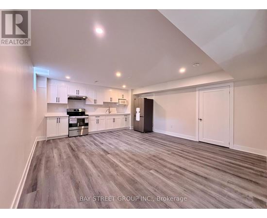 A spacious kitchen with white cabinets and a grey floor.