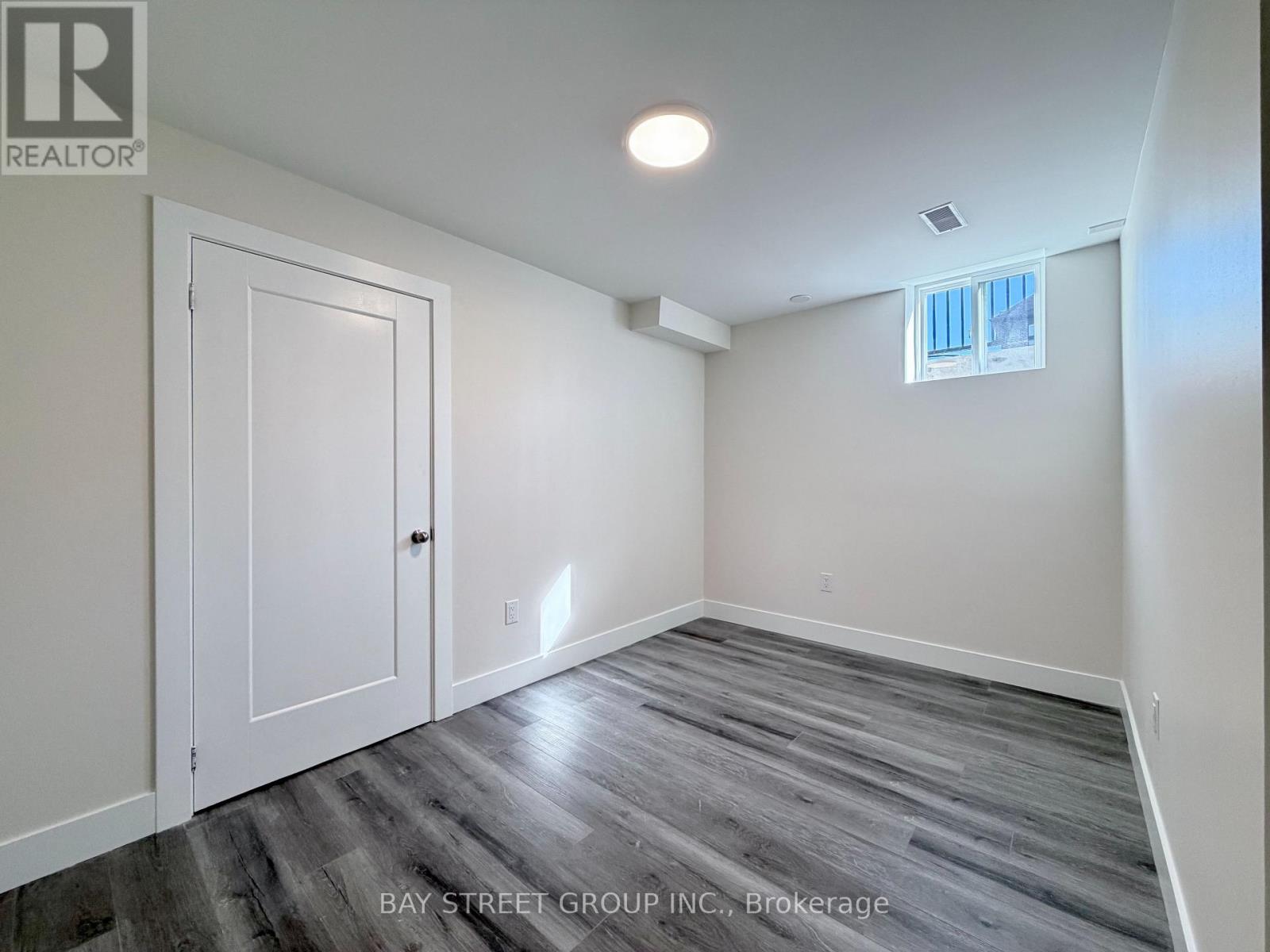 A room with a wooden floor and a window with white blinds.