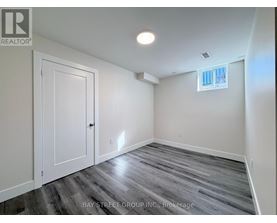 A room with a wooden floor and a window with white blinds.