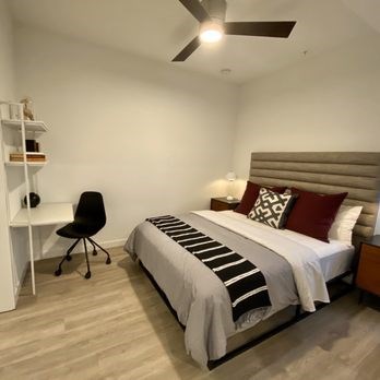 A bedroom with a bed, chair, and a shelf.