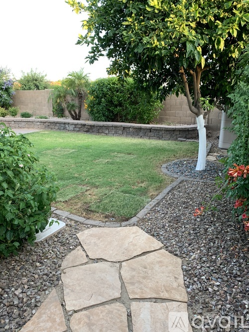 A garden with a stone pathway leading to a grassy area.