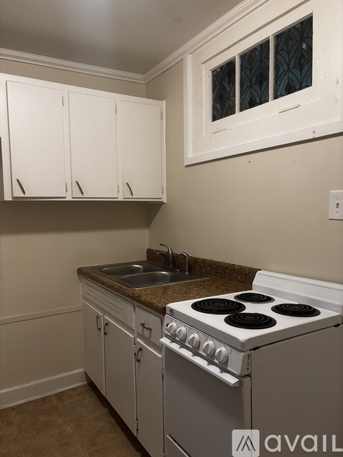 A kitchen with white cabinets and a stove top oven.