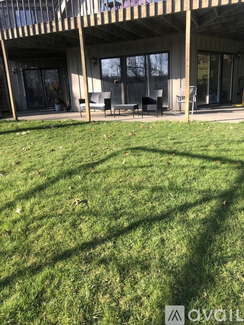 A patio with a table and chairs is surrounded by a grassy area.
