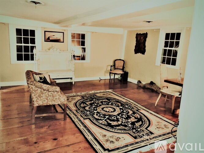 A living room with a rug, a chair, and a fireplace.