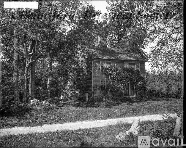 A black and white photo of a house surrounded by trees.