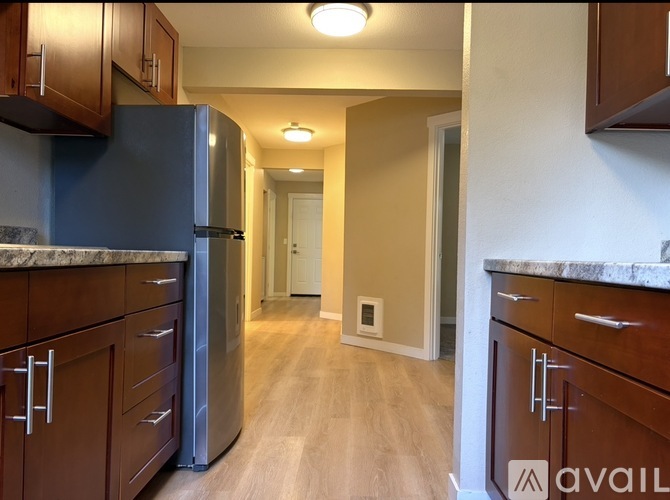 A kitchen with a black fridge and wooden cabinets.