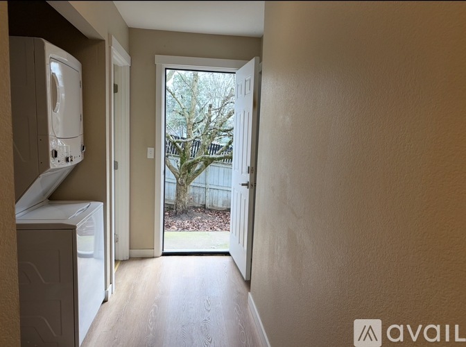 A hallway with a washer and dryer on the left and a doorway leading to a backyard.