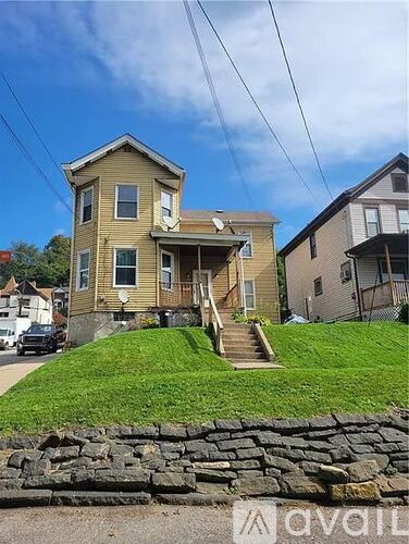 A two-story house with a stone wall in front.