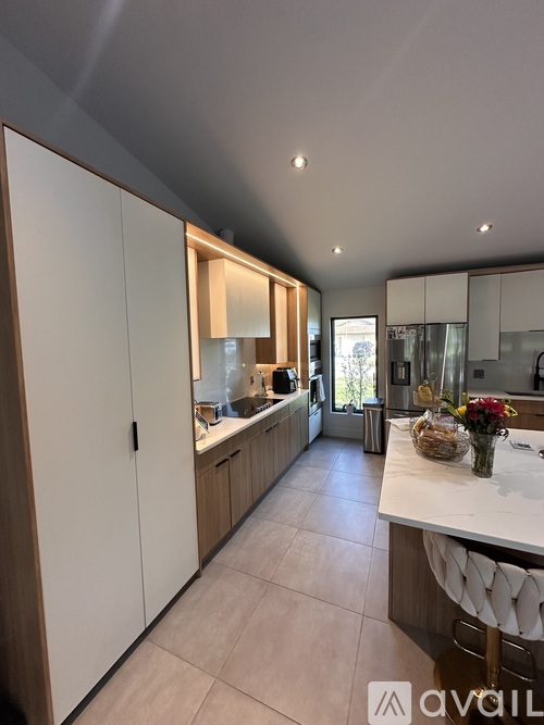 A modern kitchen with white cabinets and a marble countertop.