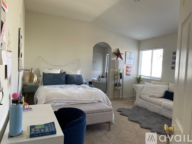 A bedroom with a white bed and a white couch.