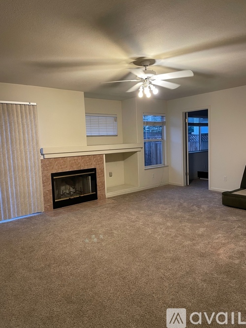 A living room with a fireplace and a ceiling fan.