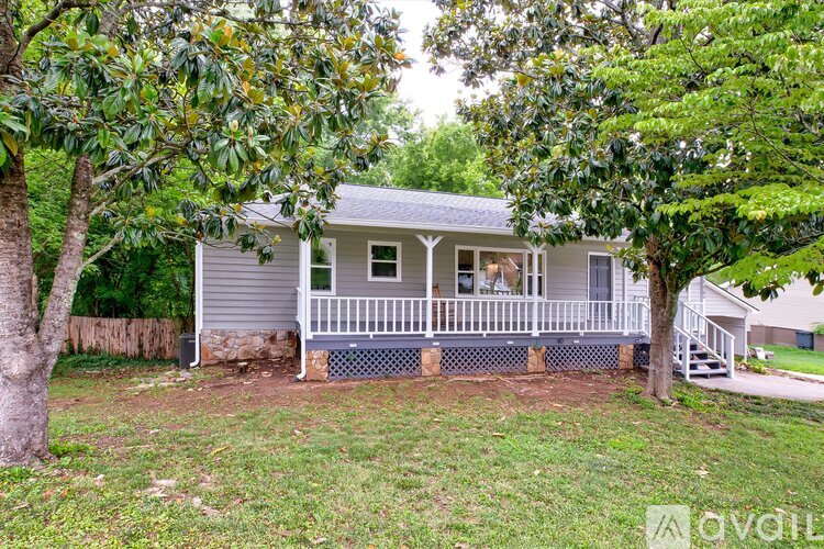 A house with a porch surrounded by trees.