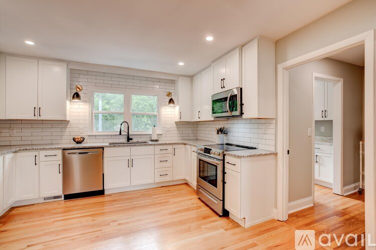 A kitchen with white cabinets and a wooden floor.