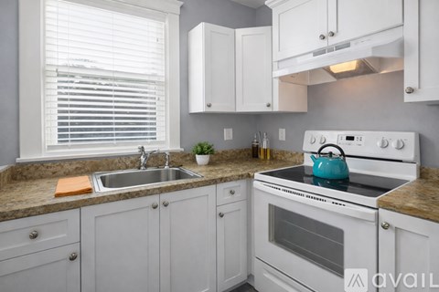 A kitchen with a white stove and cabinets.