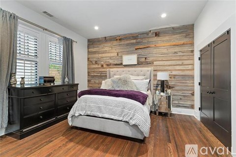 A bedroom with a bed, nightstand, and a wooden wall.