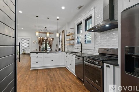 A modern kitchen with white cabinets and a wooden floor.