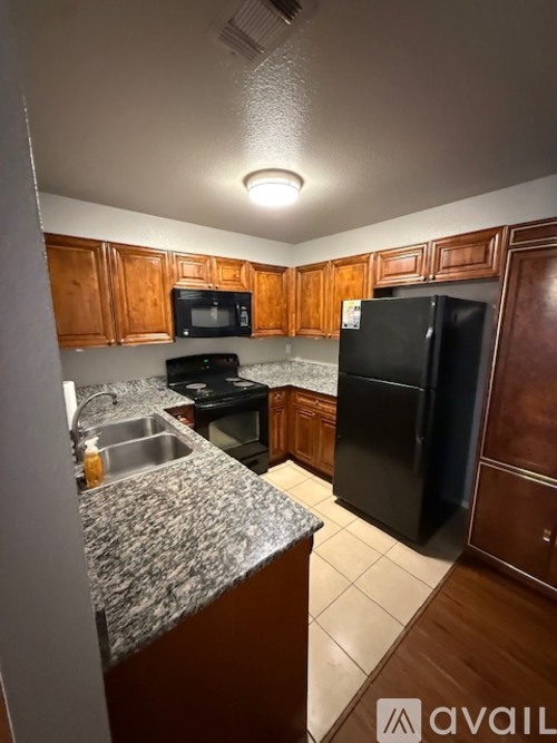 A kitchen with a black refrigerator and wooden cabinets.