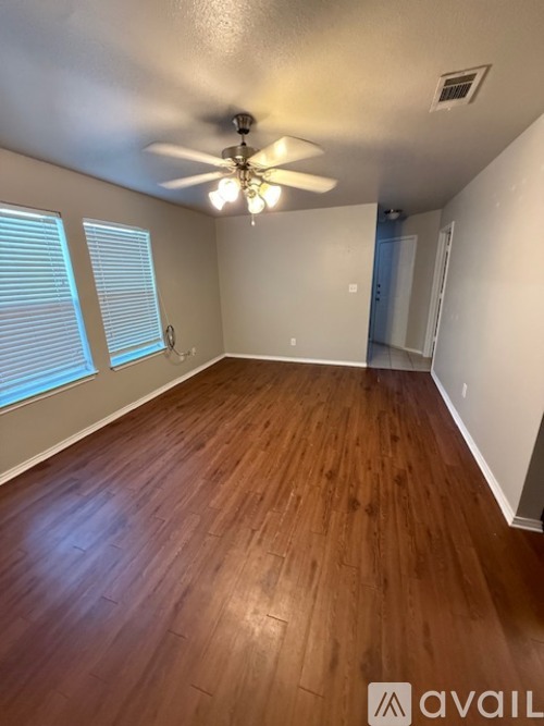 A room with wooden flooring and a ceiling fan.