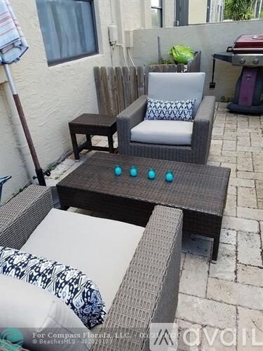 A patio with a chair, table and umbrella.