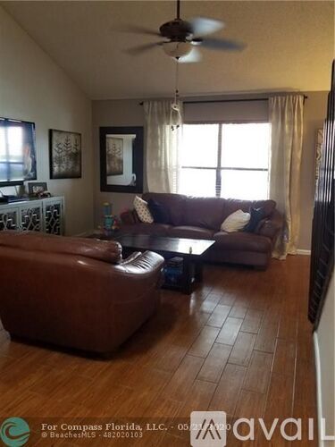A living room with a brown leather couch and a ceiling fan.