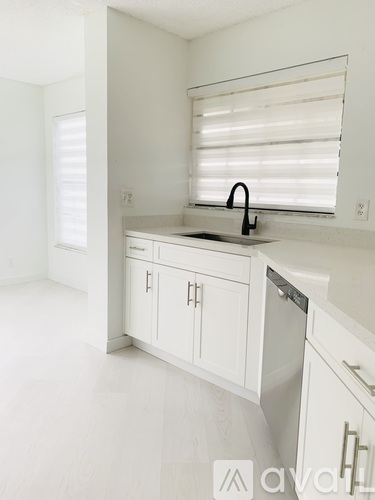 A white kitchen with a sink and cabinets.