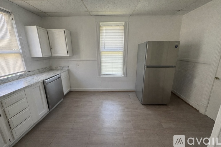 A kitchen with a refrigerator, sink, and cabinets.
