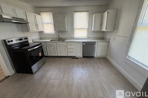 A kitchen with a black stove top oven and white cabinets.