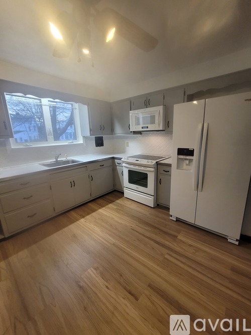 A kitchen with wooden floors and white appliances.