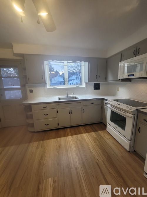 A kitchen with wooden floors and white appliances.