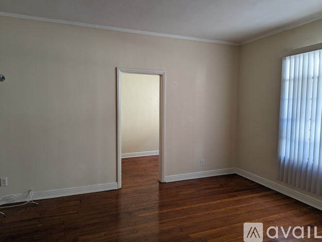 A room with wooden floors and a window with blinds.