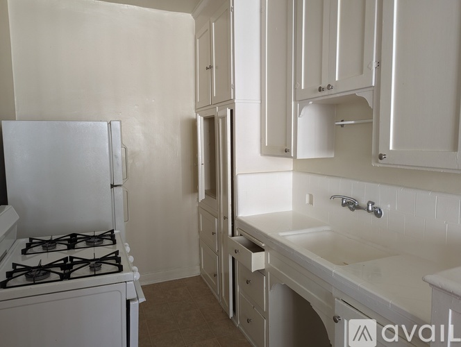 A kitchen with a white gas stove and white cabinets.