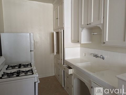 A kitchen with a white gas stove and white cabinets.