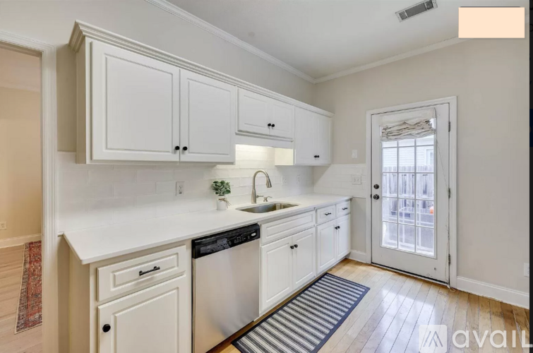 A kitchen with white cabinets and a black dishwasher.
