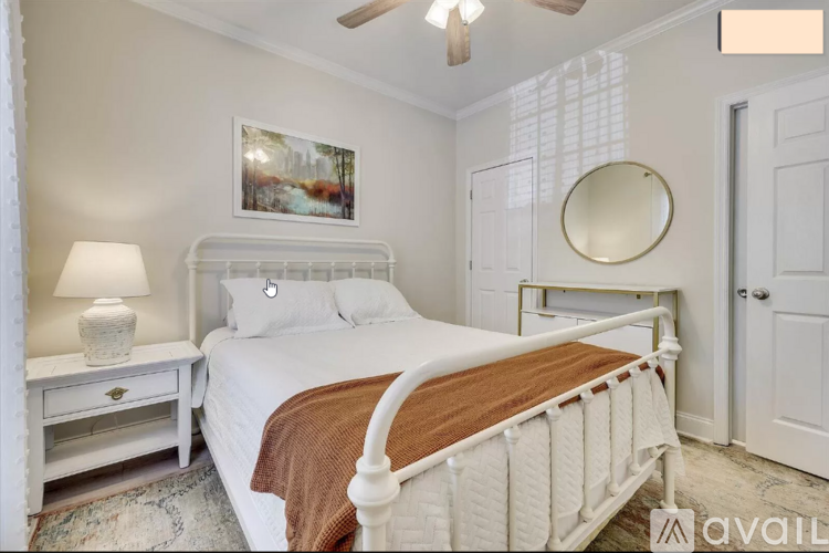 A bedroom with a white bed and a ceiling fan.
