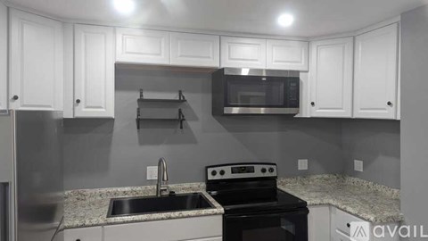 A kitchen with white cabinets and a black stove top oven.