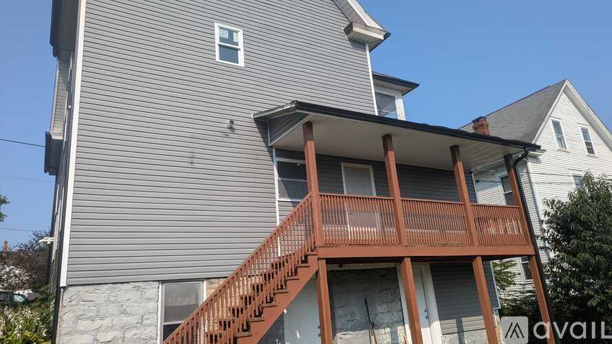 A house with a grey siding and a brown deck.