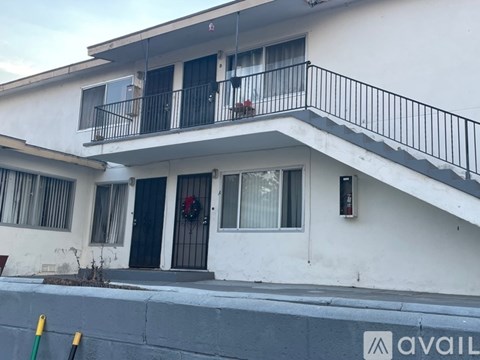 A white two-story house with a balcony on the second floor.