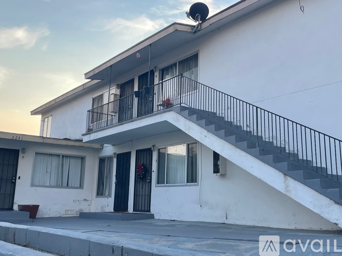 A white two-story house with a balcony and stairs leading to the second floor.