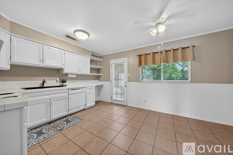 A kitchen with white cabinets and a tiled floor.