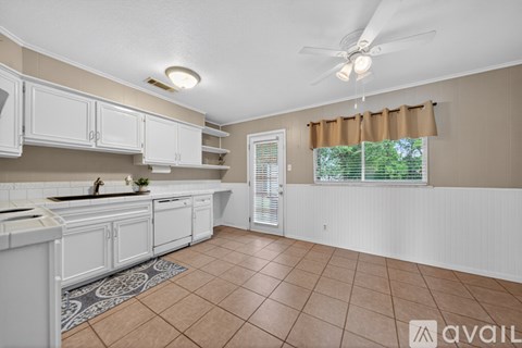 A kitchen with white cabinets and a tiled floor.