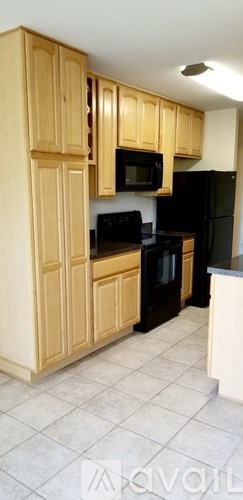 A kitchen with wooden cabinets and black appliances.