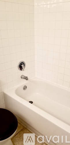 A white tiled bathroom with a white bathtub and a toilet.