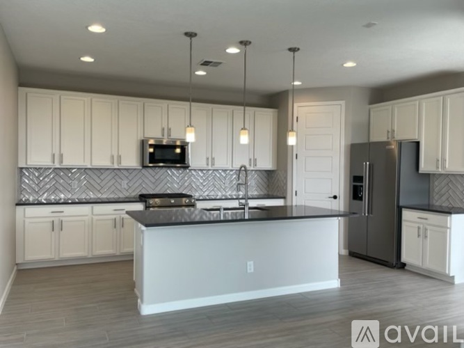 A modern kitchen with a large island and a refrigerator.
