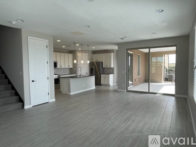 A spacious open-plan living area with a kitchen, dining area, and a staircase leading to another floor.