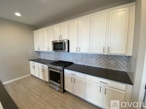 A kitchen with white cabinets and a black countertop.