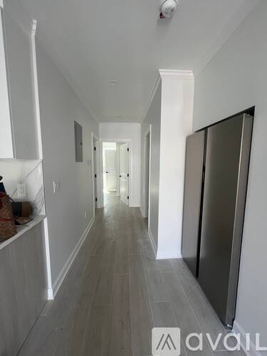 A long hallway with a refrigerator on the right side.