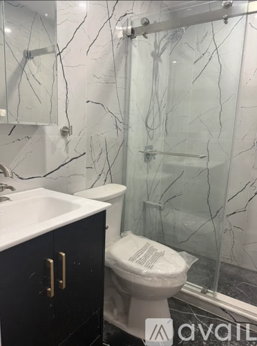 A bathroom with a toilet, sink, and glass shower enclosure.
