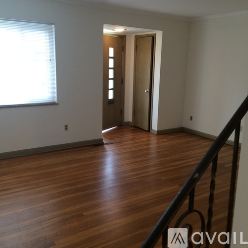 A room with wooden floors and a window with blinds.