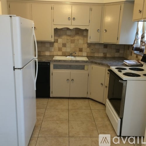 A kitchen with a white refrigerator and a white stove top oven.