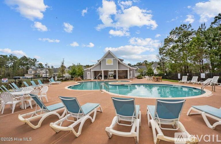 A pool surrounded by lounge chairs in front of a house.